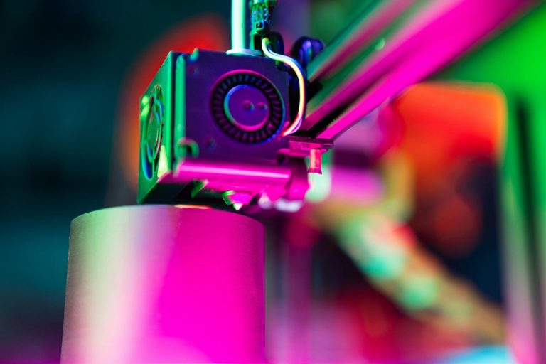 Close-up of a 3D printer in action under neon lighting, capturing vibrant colors and modern tech ambiance.